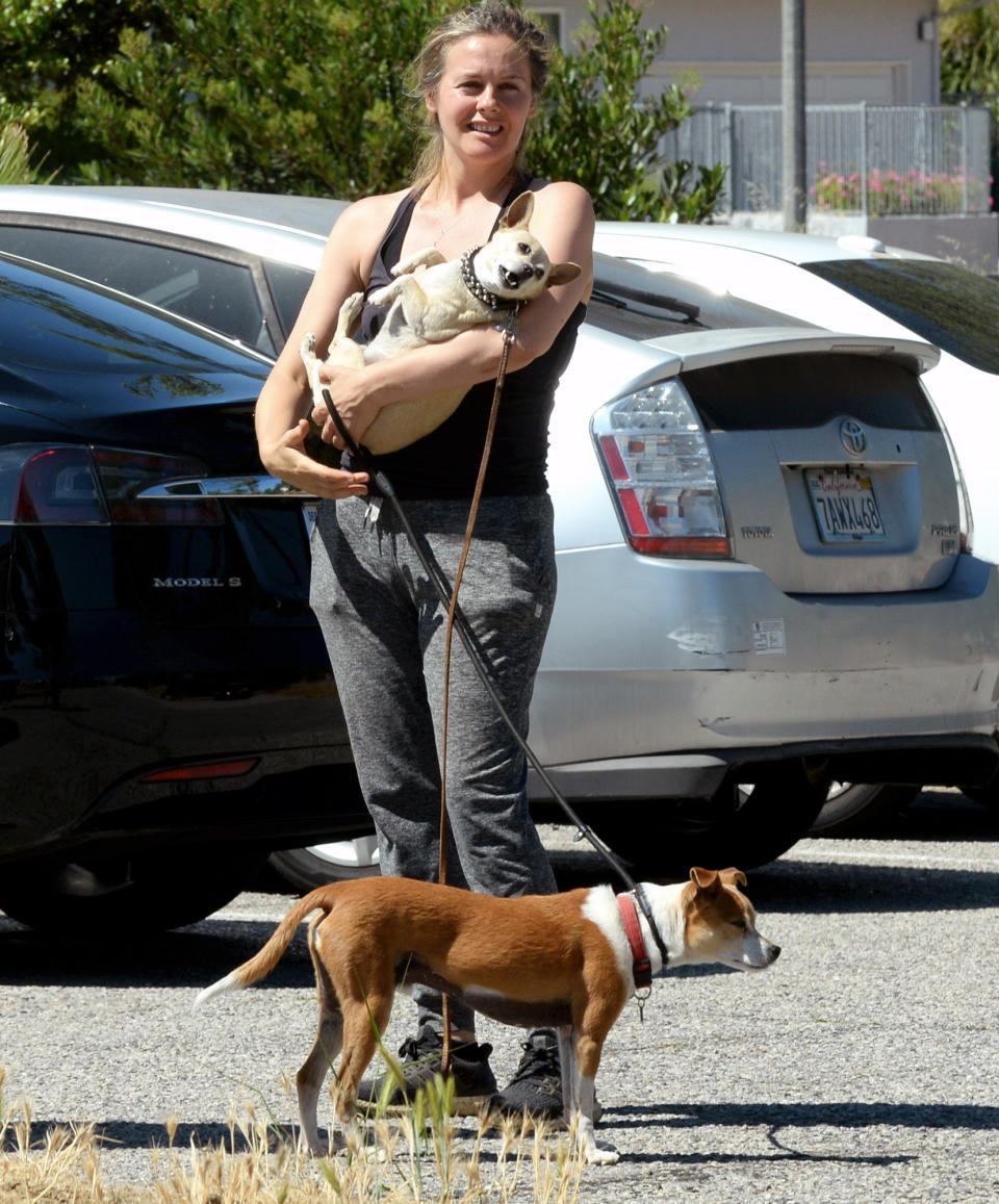 <p>Alicia Silverstone has one dog in her arms and another at her feet during a walk in L.A. on Wednesday.</p>