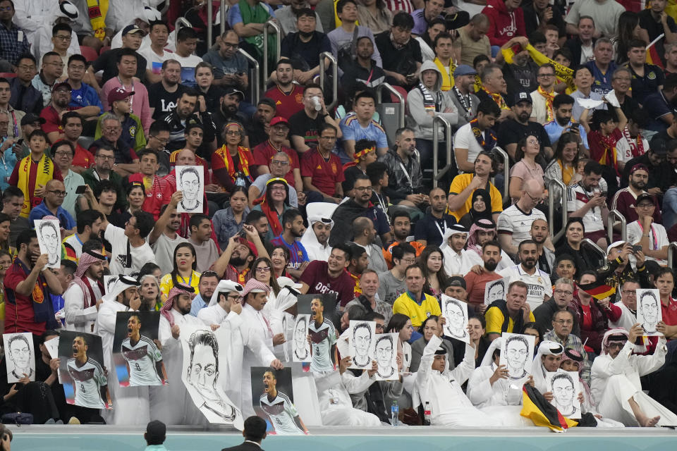 Spectators hold photos of Forman German international Mesut Ozil on the stands during the World Cup group E soccer match between Spain and Germany, at the Al Bayt Stadium in Al Khor , Qatar, Sunday, Nov. 27, 2022. (AP Photo/Matthias Schrader)