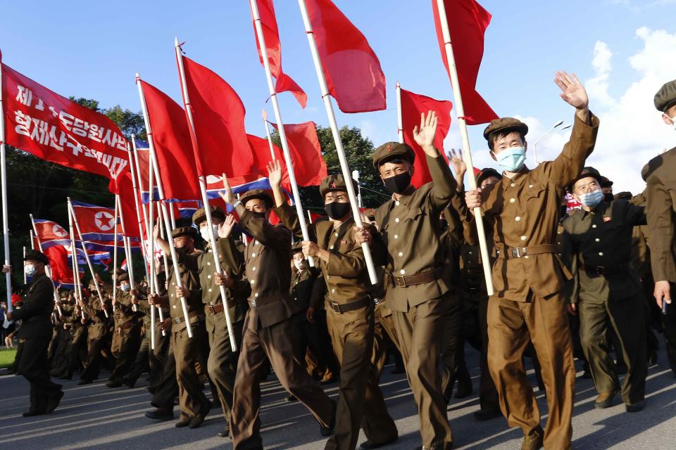 Political party members in support of the recovery efforts from typhoon damage wave during a parade at the plaza of the Kumsusan Palace of the Sun in Pyongyang, North Korea, Tuesday, Sept., 8, 2020. A powerful typhoon damaged buildings and flooded roads in North Korea on Monday, the fourth spell of strong wind and rain to hit the country in just over a month. (AP Photo/Jon Chol Jin)