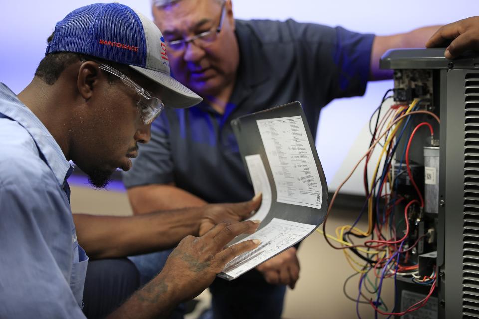 Kadarryl Joseph reads instructions with instructor Jorge Irizarry as they troubleshoot a condenser unit Aug. 10 at Snyder Air Conditioning, Plumbing & Electric in Jacksonville. A group of HVAC Technicians were part of a registered apprentice training program through Trade Up Academy and Snyder.
