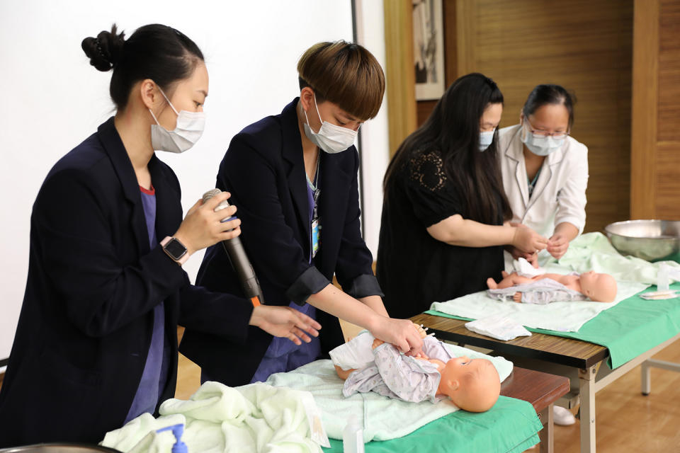 花蓮慈院護兒中心護理師曹雅晴(左一)與團隊帶著孕媽咪練習新生兒的臍帶照護。