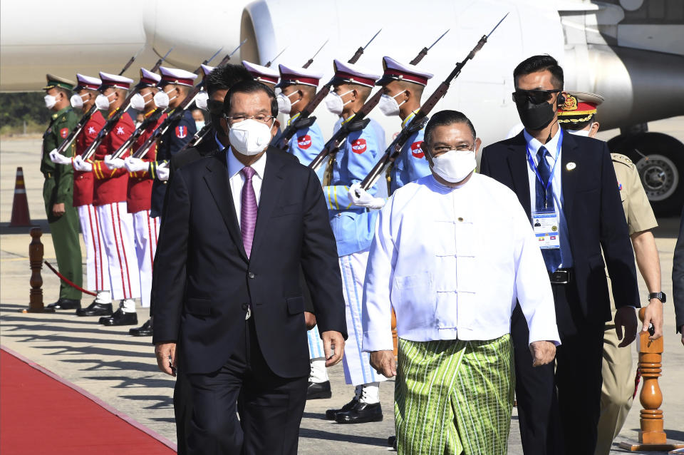 In this photo provided by An Khoun Sam Aun/National Television of Cambodia, Cambodian Prime Minister Hun Sen, front left, reviews an honor guard with Myanmar Foreign Minister Wunna Maung Lwin, front right, on his arrival at Naypyitaw International Airport in Naypyitaw, Myanmar, Friday, Jan 7, 2022. (An Khoun Sam Aun/National Television of Cambodia via AP)