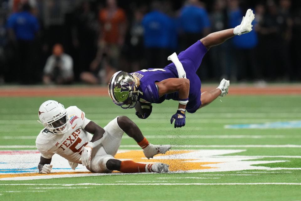 Washington wide receiver Rome Odunze is tackled by Texas defensive back D'Shawn Jamison in the second half of the 2022 Alamo Bowl at the Alamodome.