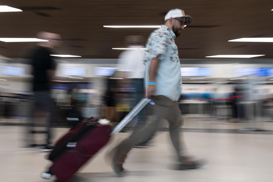 A traveler makes his way through the Nashville International Airport Thursday, May 25, 2023, in Nashville, Tenn. (AP Photo/George Walker IV)