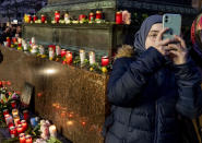 A girl takes a picture near candles as she takes part in a vigil for the victims of a shooting in Hanau, Germany Thursday, Feb. 20, 2020. A 43-year-old German man shot and killed nine people at several locations in a Frankfurt suburb overnight in attacks that appear to have been motivated by far-right beliefs, officials said Thursday. (AP Photo/Michael Probst)