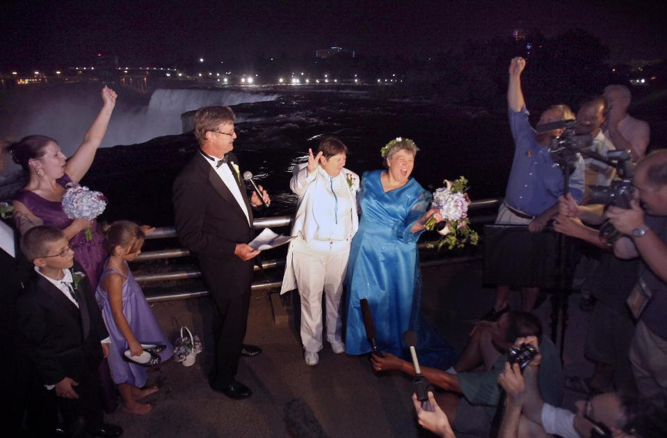 FILE - In this July 23, 2011 file photo, Kitty Lambert, right, and Cheryle Rudd celebrate their marriage in Niagara Falls, N.Y. In recent years, for economic reasons, Niagara Falls has thrown open its doors to casino gambling, gay weddings and a tightrope walk that, until laws were relaxed, would have meant arrest. It even briefly considered taking in toxic wastewater from hydraulic fracturing. On the drawing board now is a plan to entice young people to move in by paying down their student loans. (AP Photo/David Duprey, File)