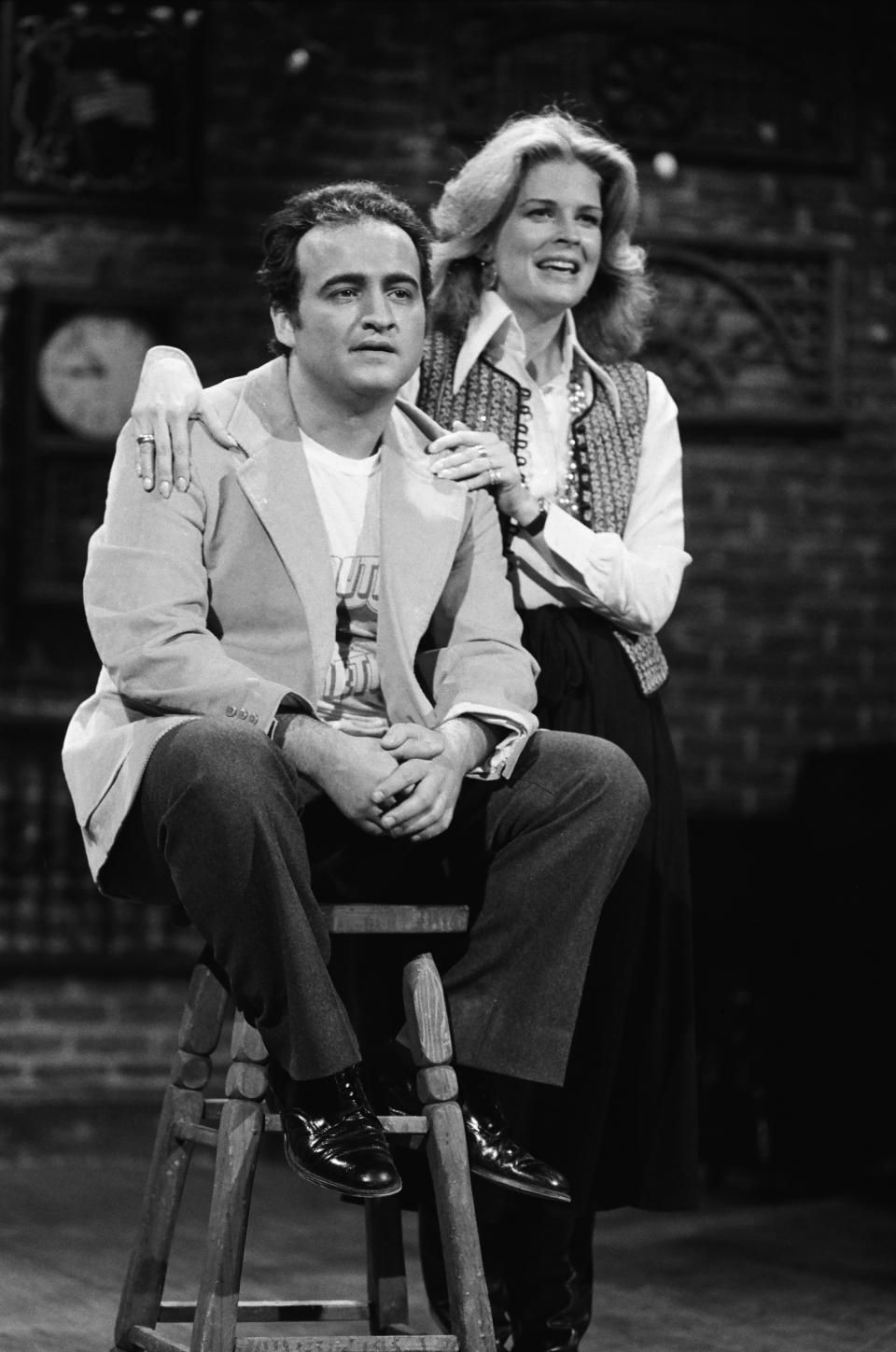 john belushi sitting on a stool