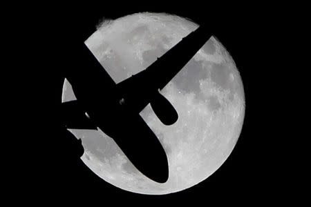 A Vueling passenger aircraft flies past a super moon in Ardales, southern Spain, October 17, 2016. REUTERS/Jon Nazca