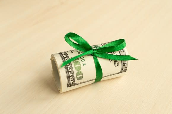 A roll of $100 bills with a green bow.