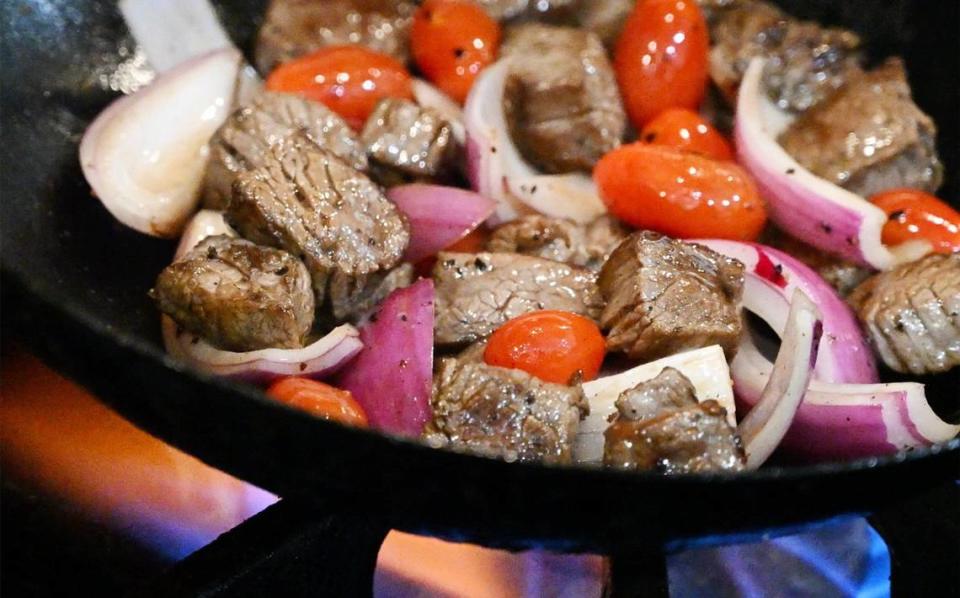 El lomo saltado de res asado al wok con cebolla y tomates se prepara en el nuevo The Third Place Global Eatery de los chefs Rob Vieira y Andrew Penn.