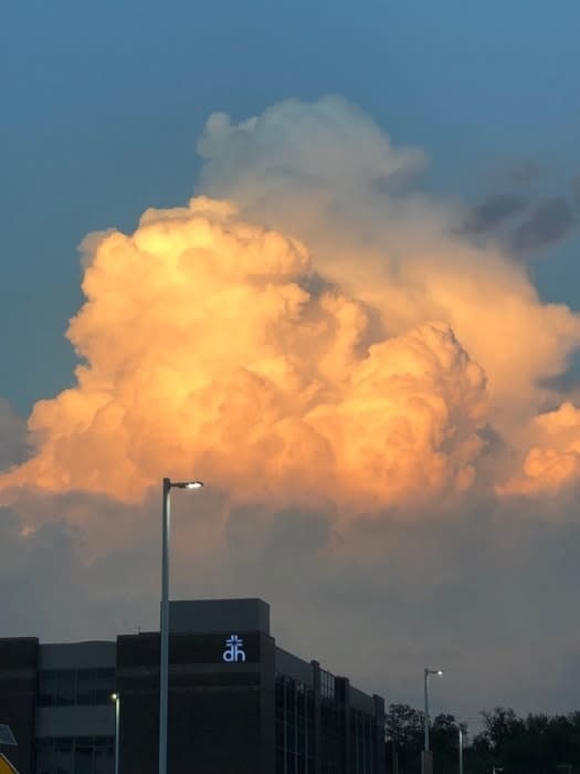 Cumulus cloud illuminated by sunset above a building