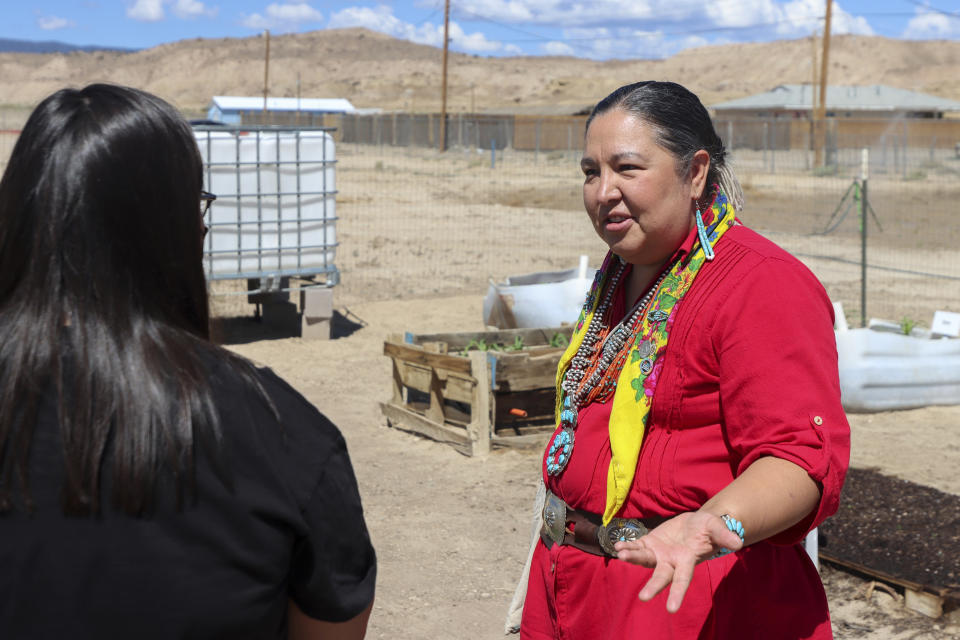 In this image provided by the Howard Center for Investigative Journalism at Arizona State University, Amber Kanazbah Crotty, a delegate to the Navajo Nation Council, speaks with a youth volunteer in a community garden at the local chapter house in Sheep Springs, N.M., on July 7, 2021. Crotty is trying to expand family advocacy centers in the Navajo Nation to better serve survivors of sexual assault and child sexual abuse. (Brendon Derr/Howard Center for Investigative Journalism/Arizona State University via AP)