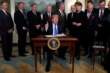 U.S. President Donald Trump, surrounded by business leaders and administration officials, prepares to sign a memorandum on intellectual property tariffs on high-tech goods from China, at the White House in Washington, U.S. March 22, 2018. REUTERS/Jonathan Ernst