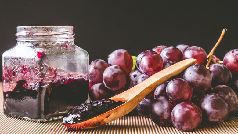 Jar of grape jelly arranged with fresh grapes