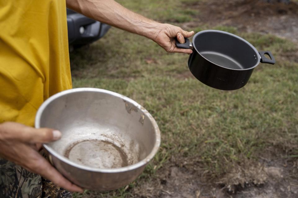 FILE - Kyle Ellison shows the pots he used to help put out a wildfire along the gorge, Sept. 27, 2023, in Kula, Hawaii. The Maui Fire Department is expected to release a report Tuesday, April 16, 2024, detailing how the agency responded to a series of wildfires that burned on the island during a windstorm last August. (AP Photo/Mengshin Lin, File)