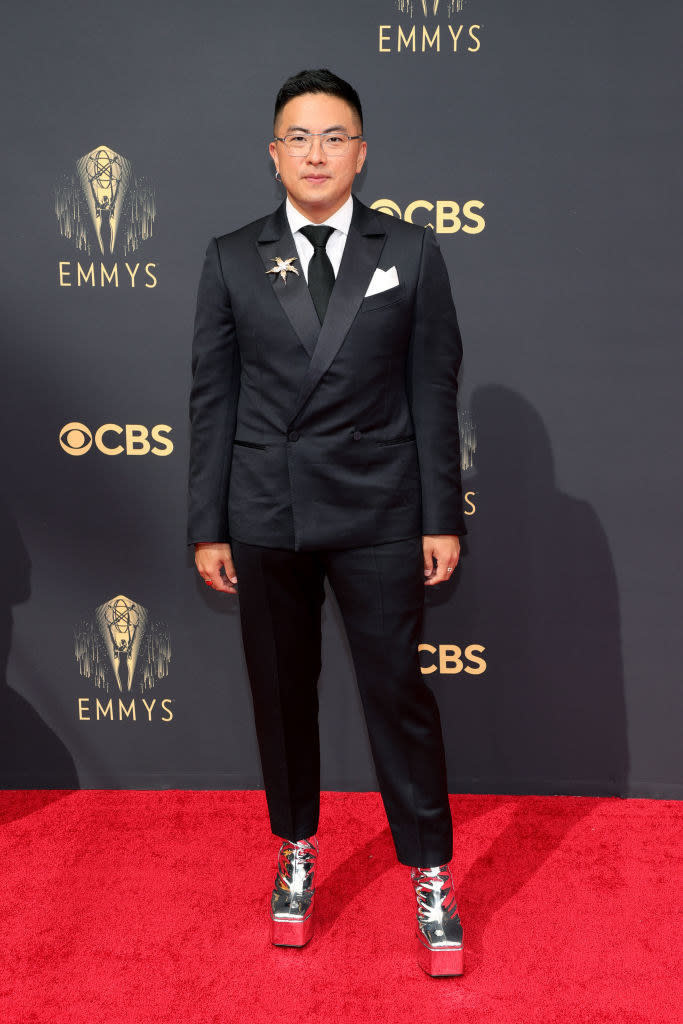 Bowen Yang on the red carpet in a black suit and silver platform heels