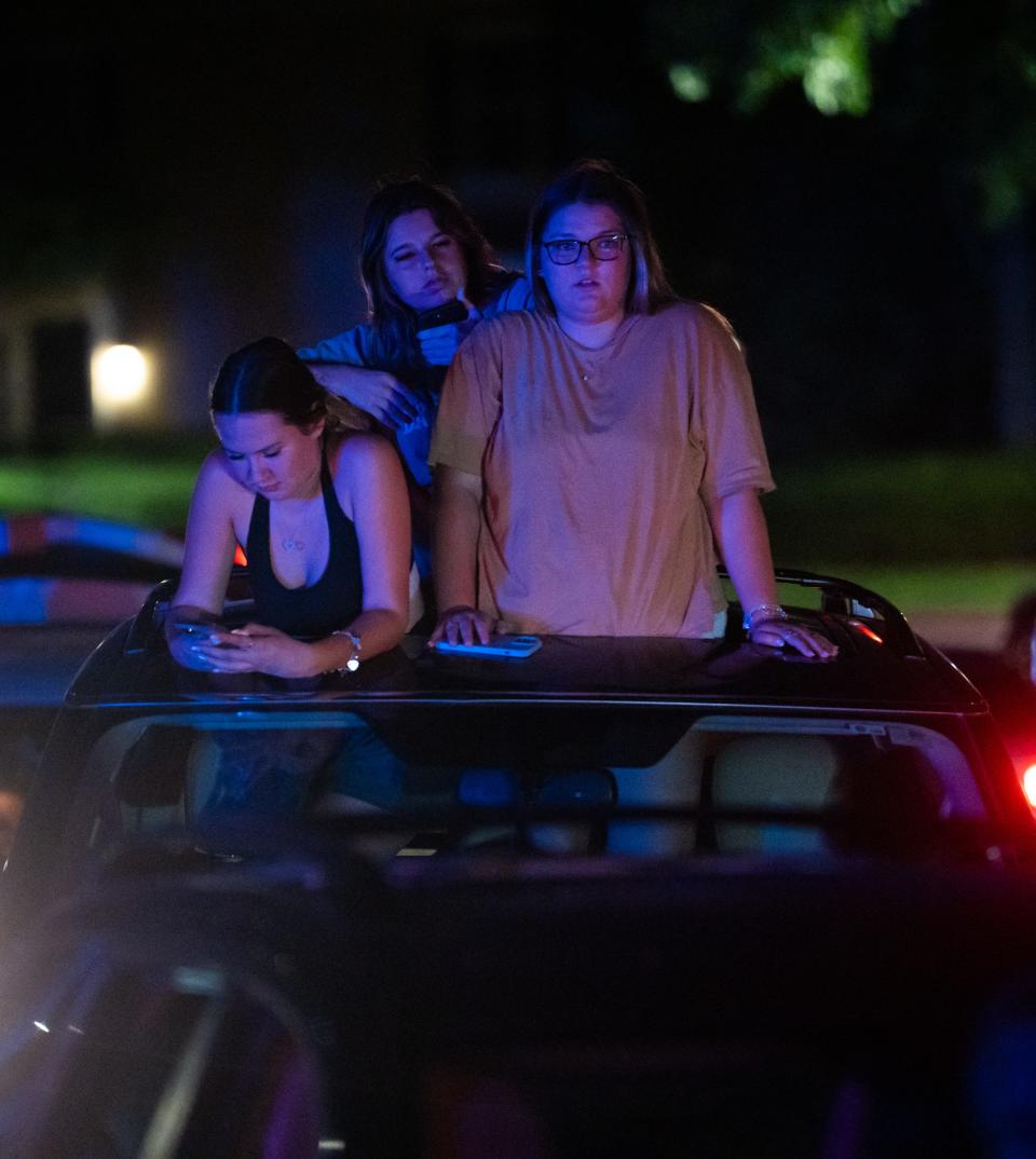 Sydni Wilson, bottom left, Taylor Lichman and Madison Horne watch as fire crews and safety officials respond to a grass fire in Cedar Park near Parmer Lane, Aug. 9, 2023.