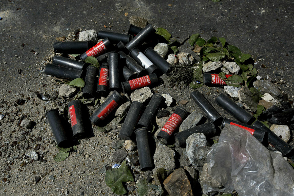 Residents of the San Jose del Avila's neighborhood collect tear gas canisters fired by Venezuelan Bolivarian National Police a day after isolated protests in response to the arrest of National Guardsmen who mounted an uprising against President Nicolas Maduro, in Caracas, Venezuela, Tuesday, Jan. 22, 2019. Working class neighborhoods in Venezuela's capital sifted through charred rubble and smoldering trash on Tuesday, after violence erupted in the streets a day prior. (AP Photo/Fernando Llano)