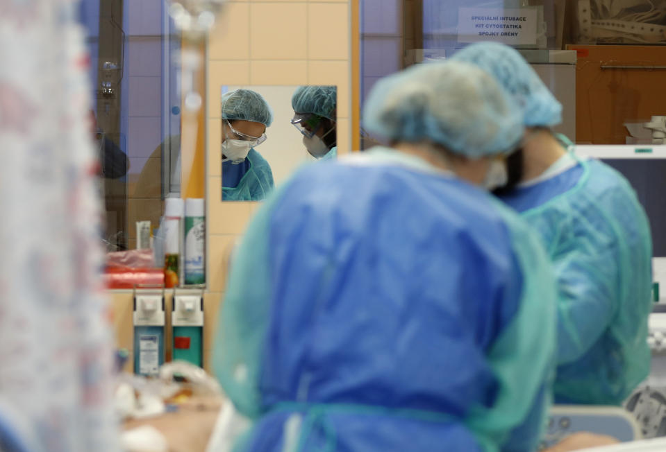 Healthcare workers attend to a COVID-19 patient in an intensive care unit (ICU) at the General University Hospital in Prague, Czech Republic, Tuesday, April 7, 2020. The new coronavirus causes mild or moderate symptoms for most people, but for some, especially older adults and people with existing health problems, it can cause more severe illness or death. (AP Photo/Petr David Josek)