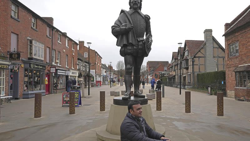 A man sits in front of the William Shakespeare statue in Stratford-upon-Avon, Warwickshire, England, Tuesday, Feb. 28, 2023. The foyer of the Other Place theater in Shakespeare’s birthplace of Stratford-upon-Avon is a cozy refuge from winter. One day a week the theater becomes a “warm hub,” set up by the Royal Shakespeare Company to welcome people who may be struggling to heat their homes because of sky-high energy prices.