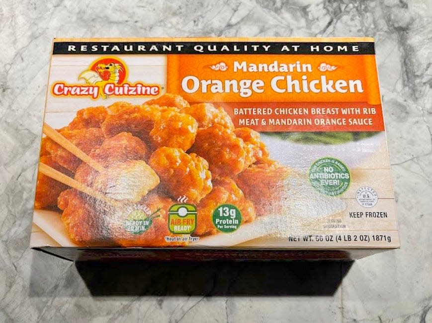 A tan box with an orange label saying "Mandarin-orange chicken" and an image of a plate of orange chicken on box