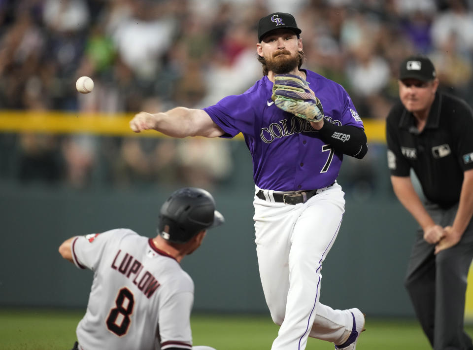 Colorado Rockies second baseman Brendan Rodgers throws over Arizona Diamondbacks' Jordan Luplow after forcing him out at second base on the front end of a double play hit into by Cooper Hummel during the sixth inning of a baseball game Saturday, July 2, 2022, in Denver. (AP Photo/David Zalubowski)