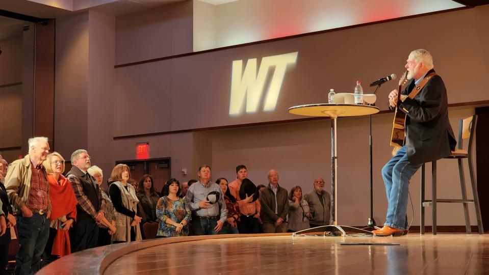 Red Steagall leads the audience in an encore rendition of "God Bless America" to close his lecture Thursday at West Texas A&M's Legacy Hall on campus.