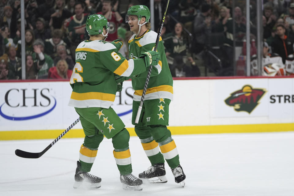 Minnesota Wild defensemen Jon Merrill, right, celebrates with Dakota Mermis (6) after scoring against the Anaheim Ducks during the first period of an NHL hockey game Saturday, Jan. 27, 2024, in St. Paul, Minn. (AP Photo/Abbie Parr)