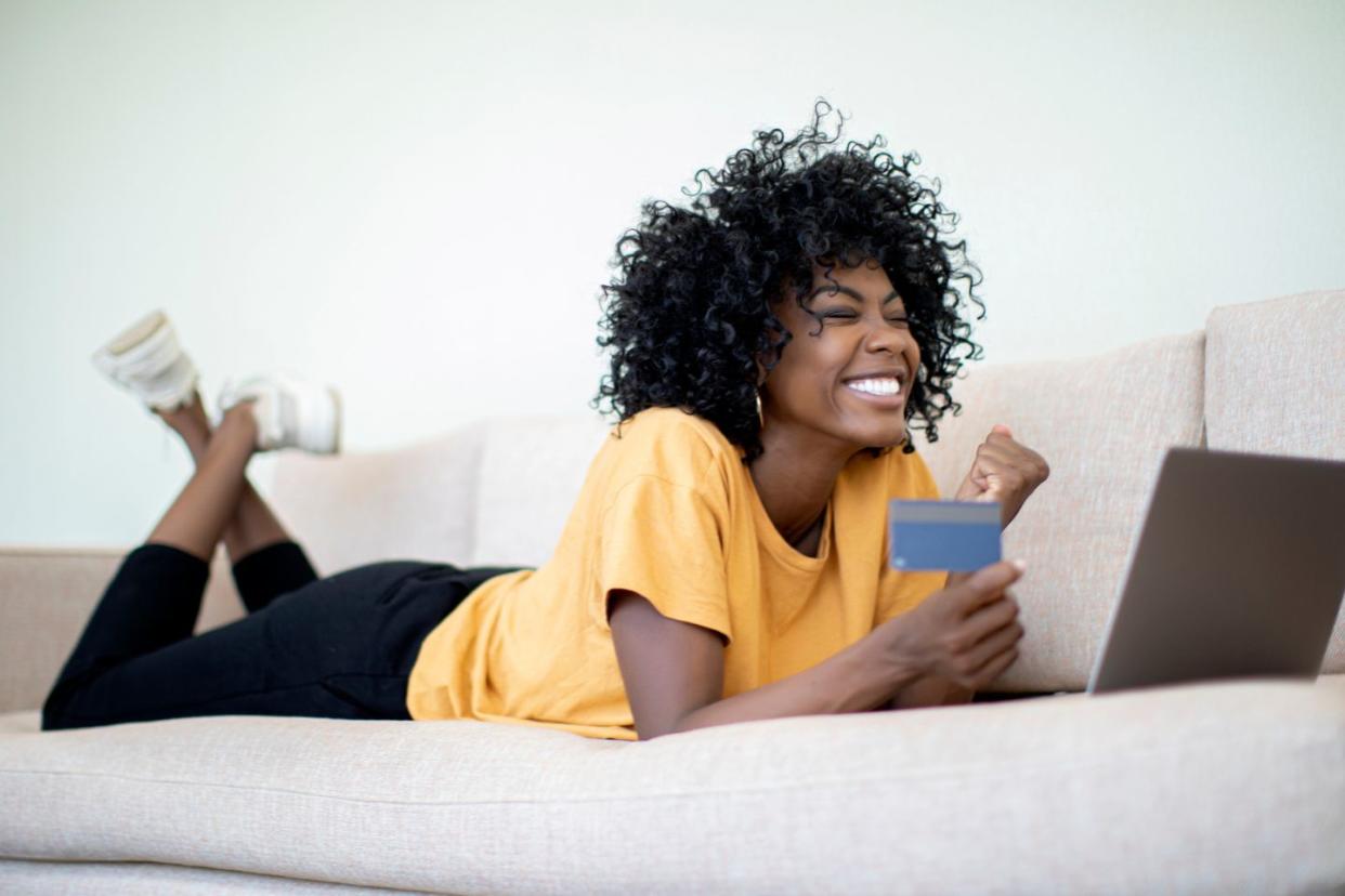 woman excitedly shopping online with credit card in hand