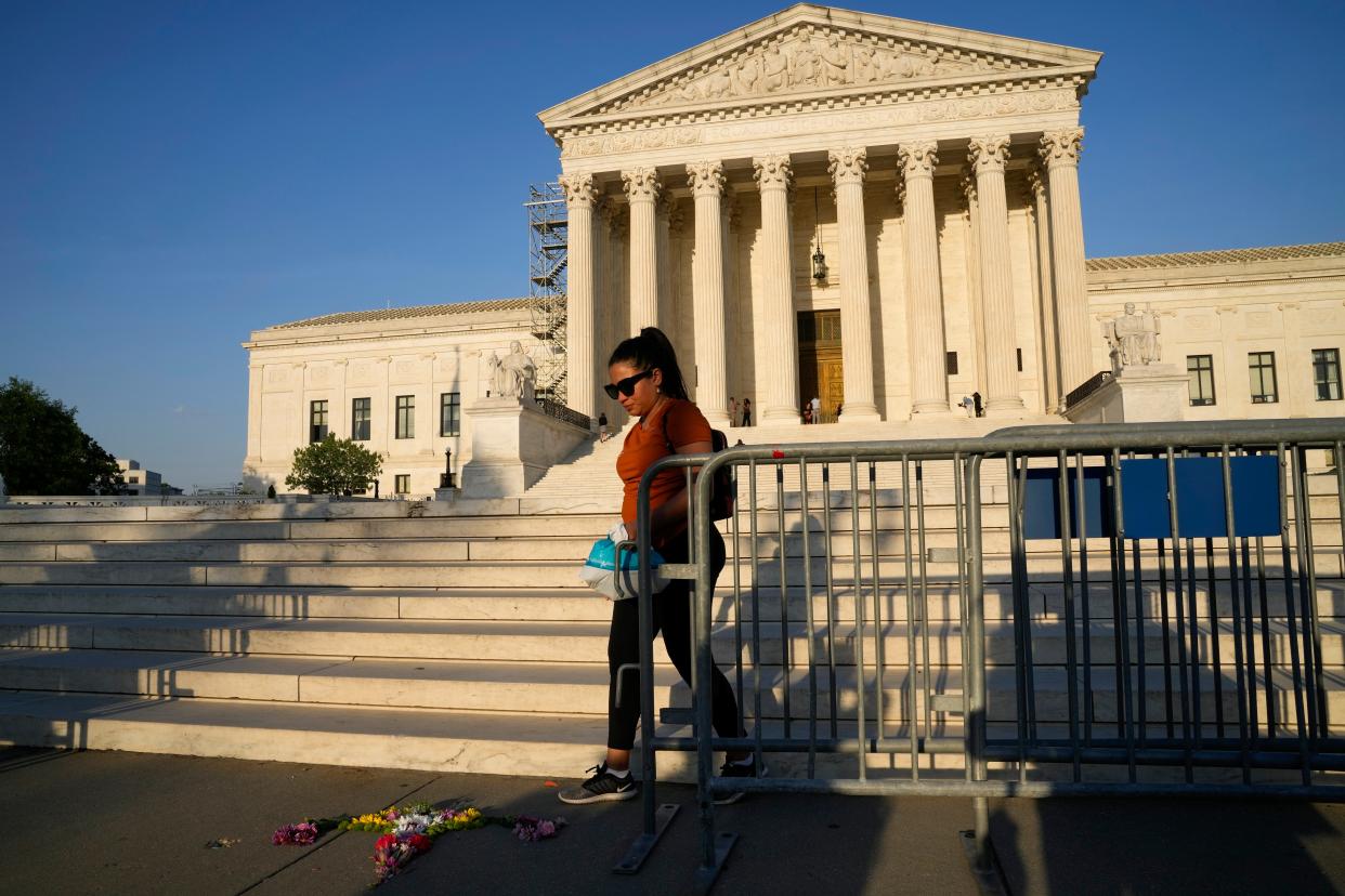 A person walks by flowers that are in the shape of a uterus outside the Supreme Court on Friday, April 21, 2023, in Washington.