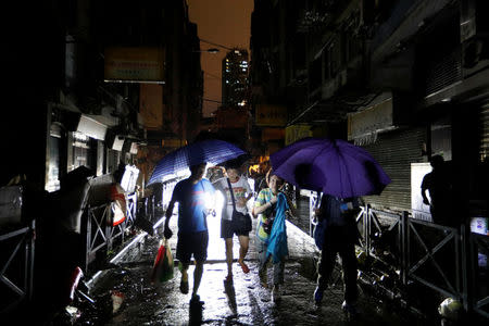 People walk on a street during a power outage after Typhoon Hato hit in Macau, China August 24, 2017. REUTERS/Tyrone Siu