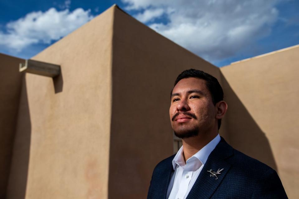 A man stands beneath a blue sky near a beige building