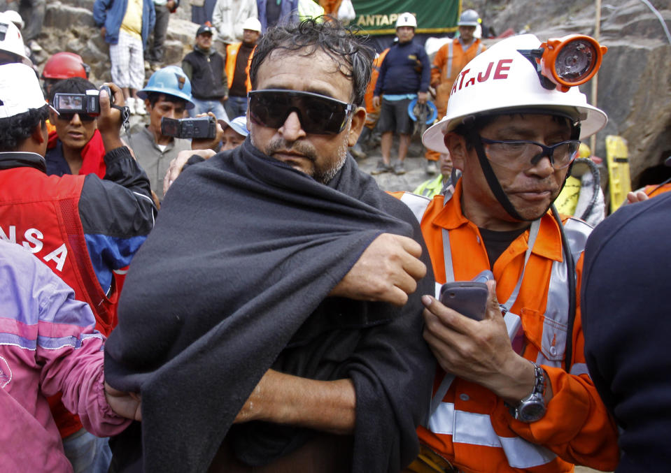 An unidentified miner, left, is helped by an emergency worker after being rescued from the Cabeza de Negro gold-and-copper mine in Yauca del Rosario, Peru, Wednesday April 11, 2012.  Nine miners had been trapped inside a wildcat mine since April 5.  (AP Photo/Martin Mejia)