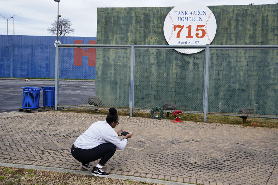 Krystal Dixon takes a photo in front of Hank Aaron's home run wall, left from when Atlanta's Fulton County Stadium was demolished, where Aaron hit his 715th home run on April 8, 1974 to break the career home run record held by Babe Ruth. Hank Aaron died Friday, Jan. 22, 2021. He was 86. (AP Photo/John Bazemore)