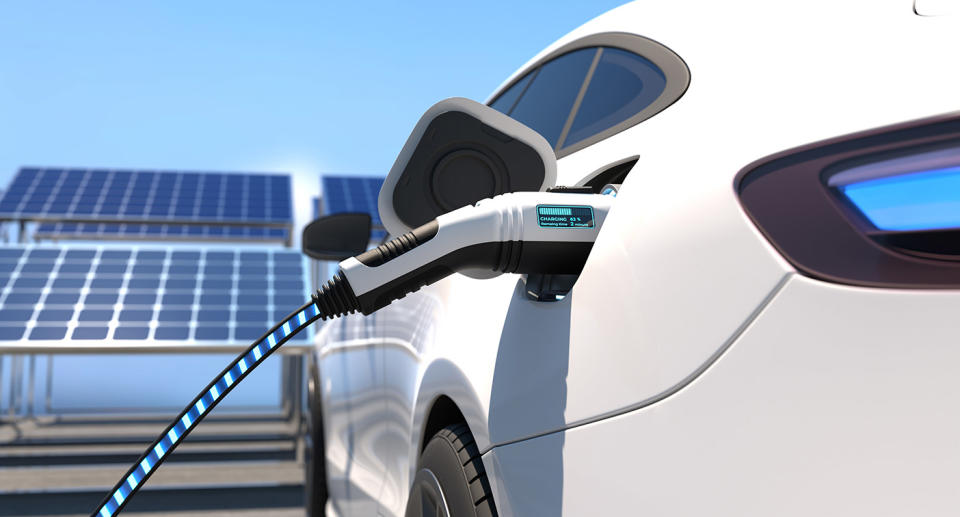 Electric car charging in front of solar panels