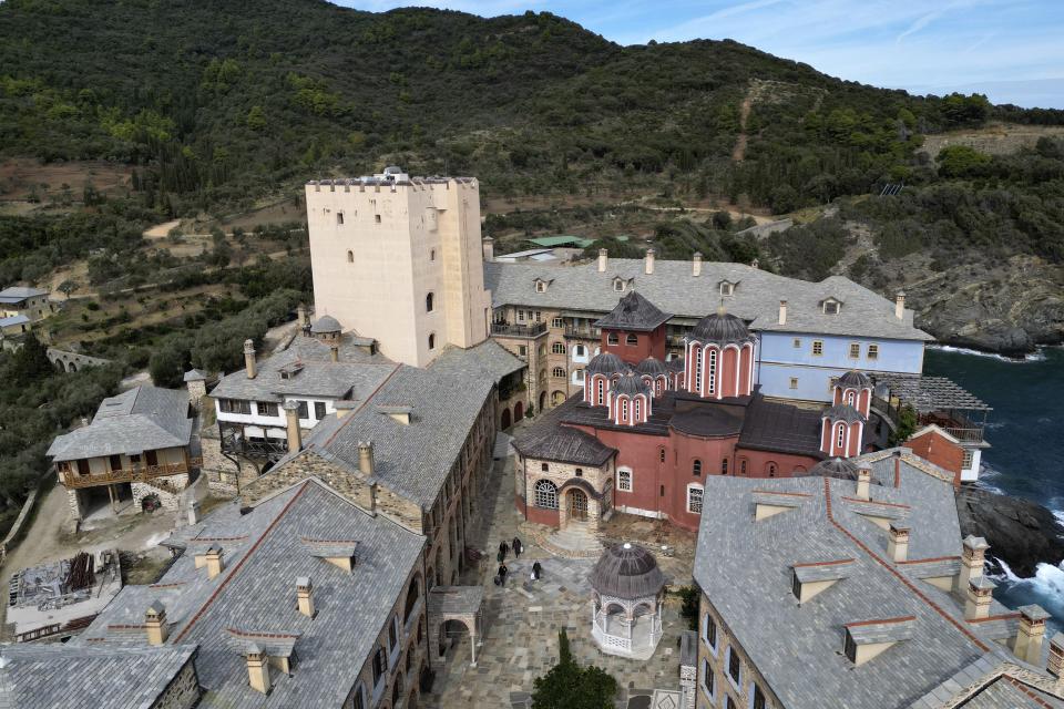 The tower with the library stands on the left, as visitors arrive at the Pantokrator Monastery in the Mount Athos, northern Greece, on Thursday, Oct. 13, 2022. Deep inside a medieval fortified monastery in the Mount Athos monastic community, researchers are for the first time tapping a virtually unknown treasure: thousands of Ottoman-era manuscripts that include the oldest of their kind in the world. (AP Photo/Thanassis Stavrakis)