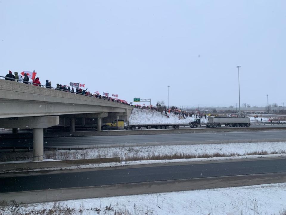 People lined the Wellington Road overpass in London, Ont., on Thursday, waving to truckers travelling from Windsor and Chatham, then it was onward to Ottawa to protest COVID-19 vaccine mandates.  (Kate Dubinski/CBC - image credit)