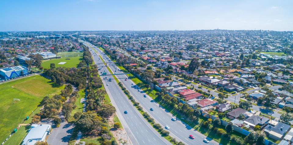 Cars driving on Monash freeway through Wheelers Hill suburb in Melbourne, Australia on sunny day - aerial panorama