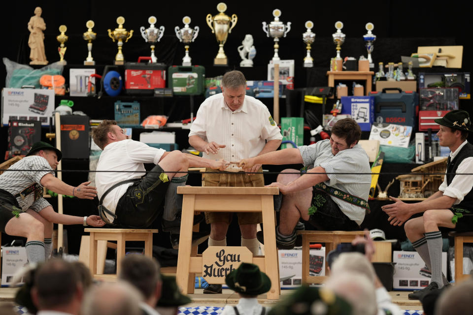 A referee monitors the leather ring held by two competitors with their middle fingers at the German Championships in Fingerhakeln or finger wrestling, in Bernbeuren, Germany, Sunday, May 12, 2024. Competitors battled for the title in this traditional rural sport where the winner has to pull his opponent over a marked line on the table. (AP Photo/Matthias Schrader)