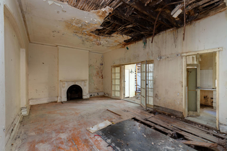 Inside of a rundown Darlinghurst home in Sydney is pictured with the ceiling caving in and floorboards ripped up.