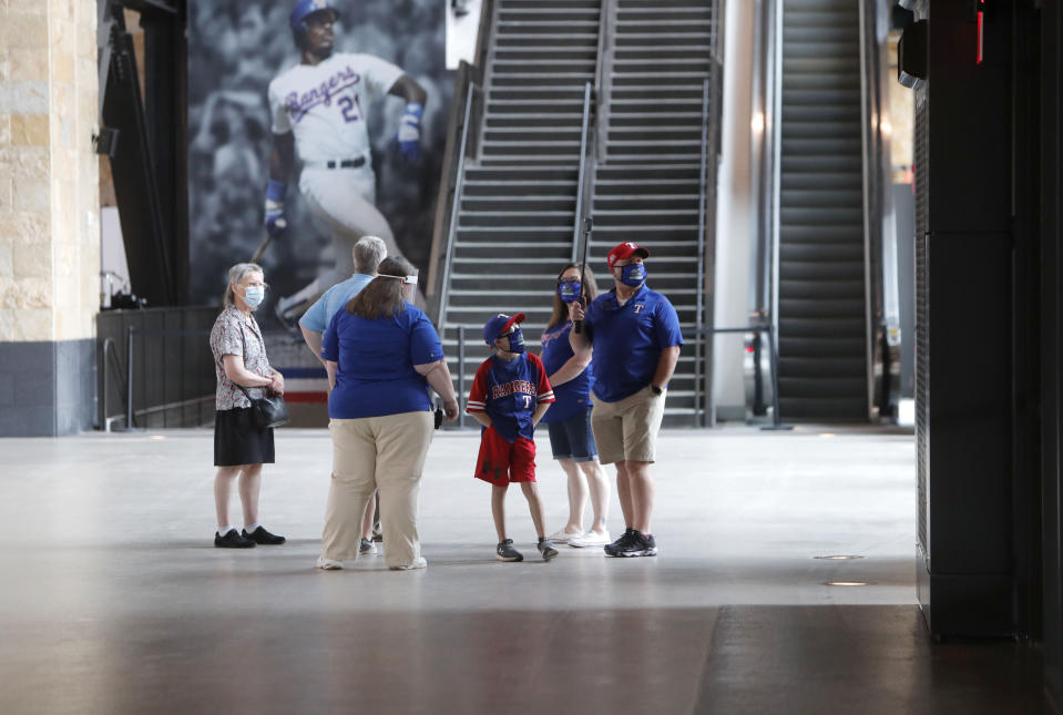 Baseball fans check out the concourse at Globe Life Field, the new home of the Texas Rangers baseball team, during the first day of public tours Monday, June 1, 2020, in Arlington, Texas. As lock-downs are lifted, restrictions on social gatherings eased and life begins to resemble some sense, sports are finally starting to emerge from the coronavirus pandemic. Major League Soccer, the NBA and NHL have agreements in place to restart their seasons, and baseball is going through contentious rounds of negotiations over what it might take for umpires to cry “Play Ball!” and America's pastime to provide a weary public some much-needed entertainment.(AP Photo/LM Otero, File)