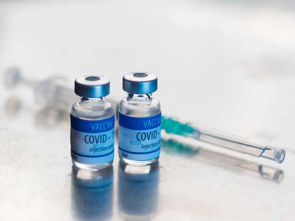 COVID-19 vaccine vials next to a syringe.