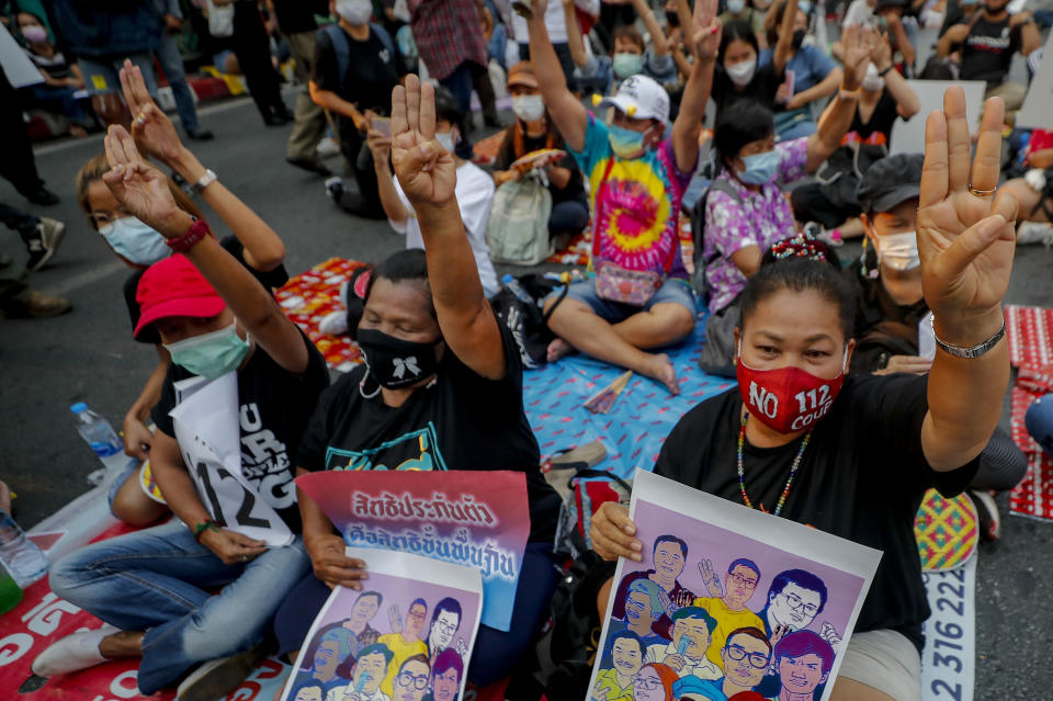 Pro-democracy activists flash a three-fingered symbol of resistance during a rally in Bangkok, Thailand, Wednesday, March 24, 2021, ahead of indictment against 13 protest leaders on Thursday for allegations of sedition and defaming the monarchy. (AP Photo/Sakchai Lalit)