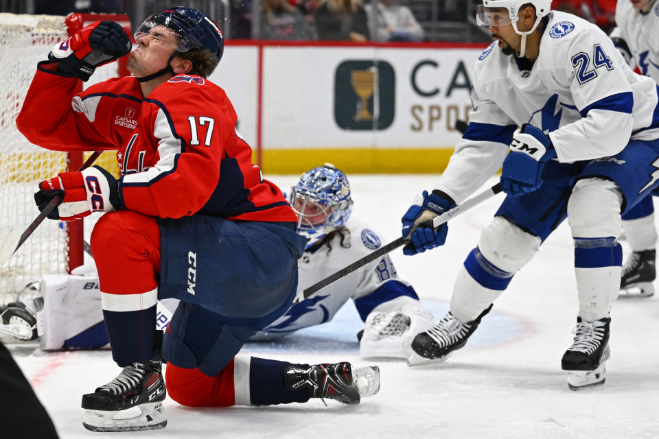 Washington Capitals center Dylan Strome (17) reacts to getting hit on the face, while Tampa Bay Lightning defenseman Matt Dumba (24) clears the puck in front of the net during the second period of an NHL hockey game Saturday, April 13, 2024, in Washington. (AP Photo/John McDonnell)