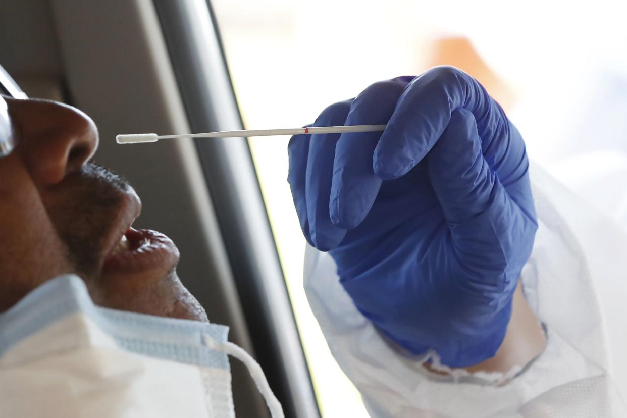 In this April 16, 2020 photo, a man braces for a nasal swab by one of the Delta Health Center staff at a free drive-thru COVID-19 testing facility in Mound Bayou, Miss.