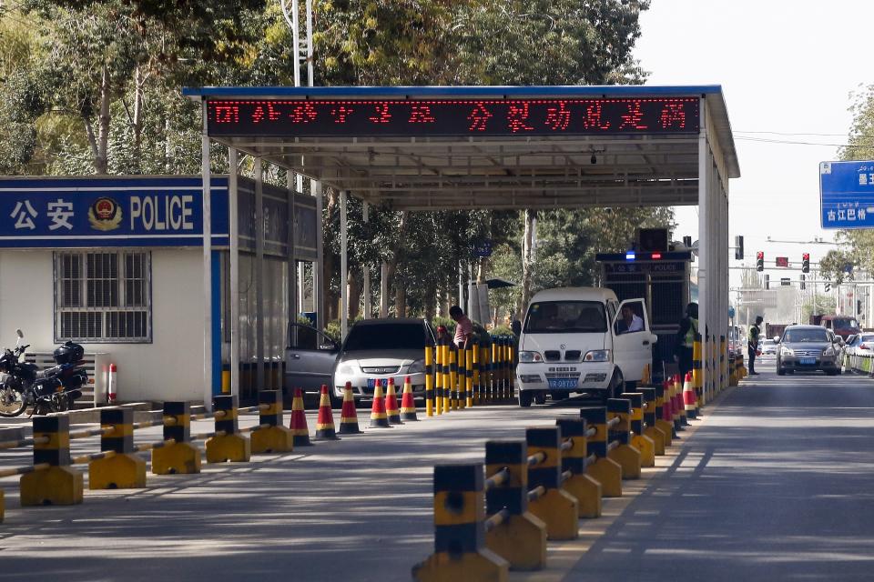 In this Sept. 21, 2018, photo, Uighur drivers have their vehicles checked at a police check point in Hotan, in western China's Xinjiang region. While thousands of Uighur Muslims across China’s Xinjiang region are forced into re-education camps, China’s fledgling vision for ethnic unity is taking shape in a village where Han Chinese work and live alongside Uighur minorities. (AP Photo/Andy Wong)