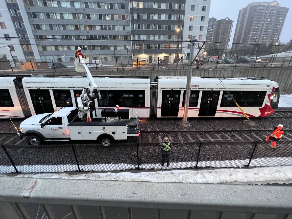 Crews work on a stalled LRT train near Lees station Thursday. As of 4:45 p.m., trains were still not running between uOttawa and Blair station following a bout of freezing rain that caused ice buildup on the overhead power system. (David Bates-Taillefer/CBC - image credit)