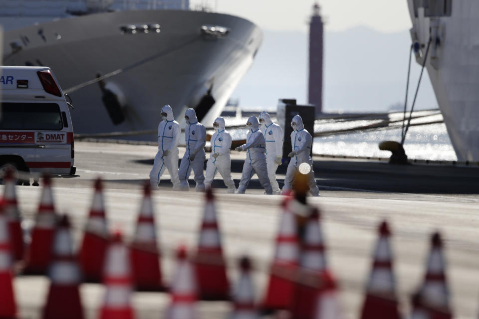 Medical workers with protective suites walk away from the quarantined Diamond Princess cruise ship in Yokohama, near Tokyo, Tuesday, Feb. 11, 2020. Japan's Health Minister Katsunobu Kato said the government was considering testing everyone remaining on board and crew on the Diamond Princess, which would require them to remain aboard until results were available. (AP Photo/Jae C. Hong)
