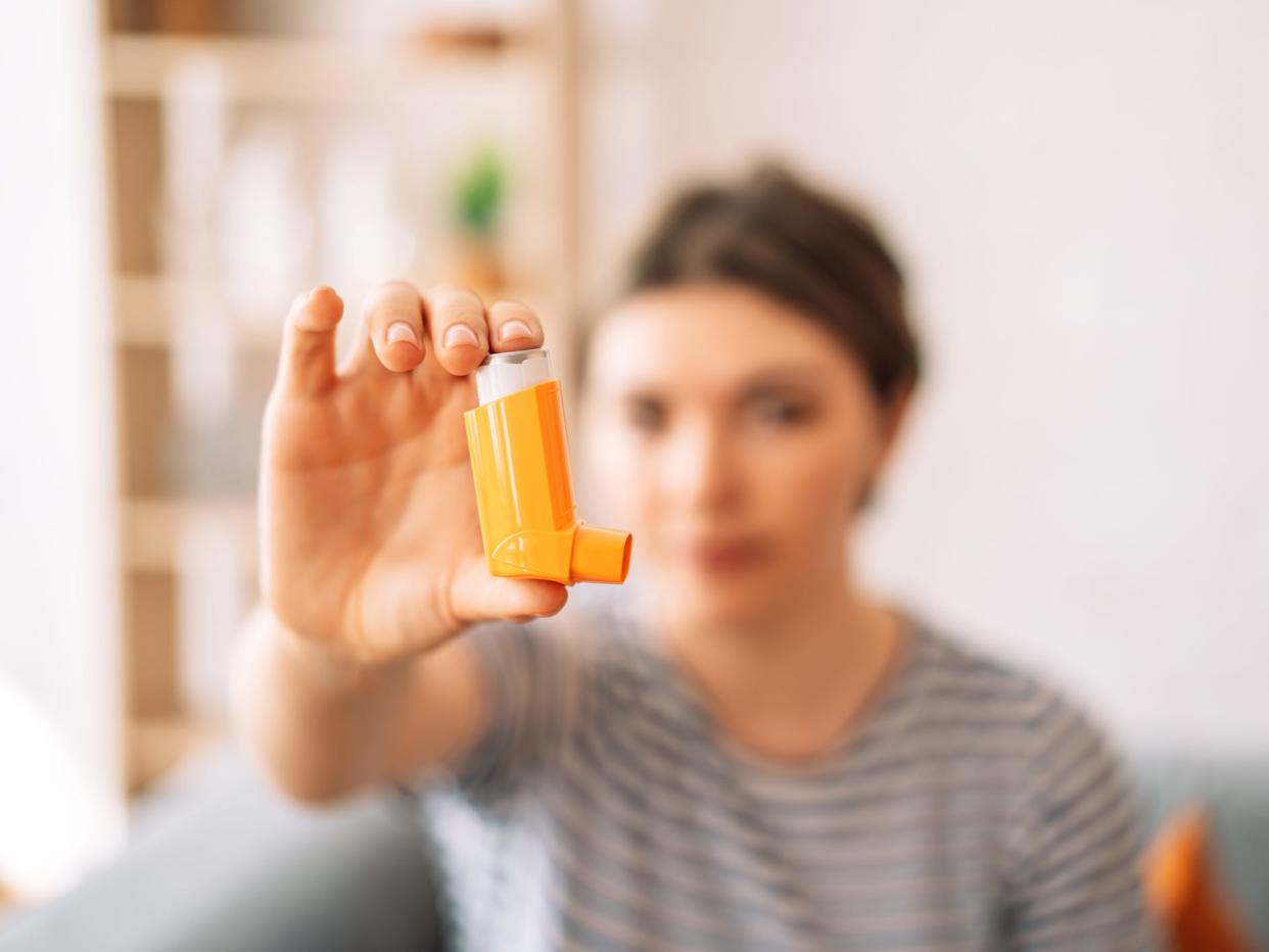 Woman in background holding inhaler to the foreground of the picture