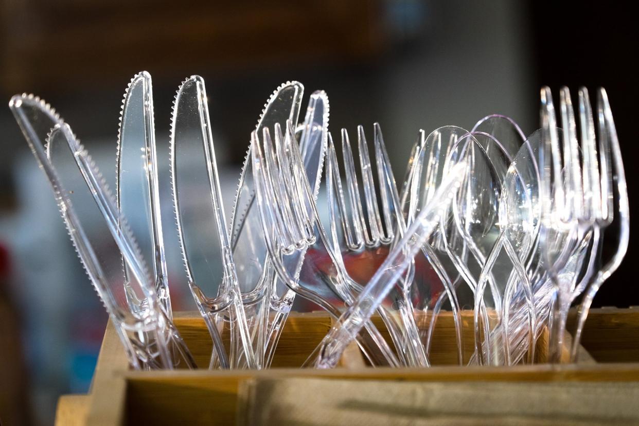 clear plastic knives, forks, and spoons in a wooden box